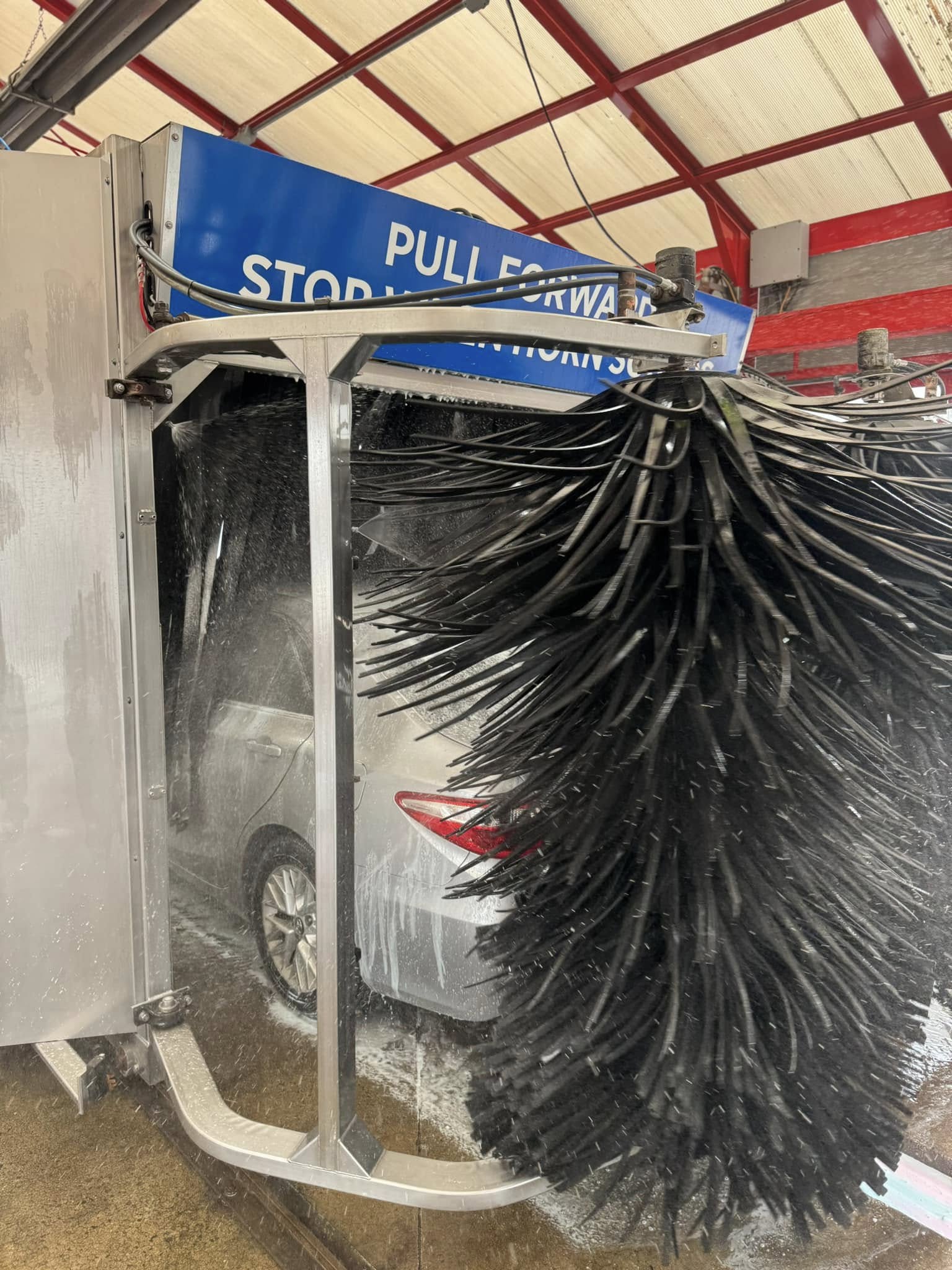 A close up photo of a silver car running through car wash brushes at Clean Car Wash and Detail in Fredericksburg, VA.