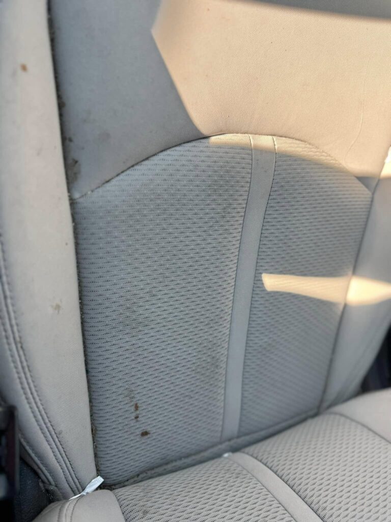 The before photo of the dirty seat of a vehicle before a car detailing appointment at Clean Car Wash and Detail in Fredericksburg, VA.