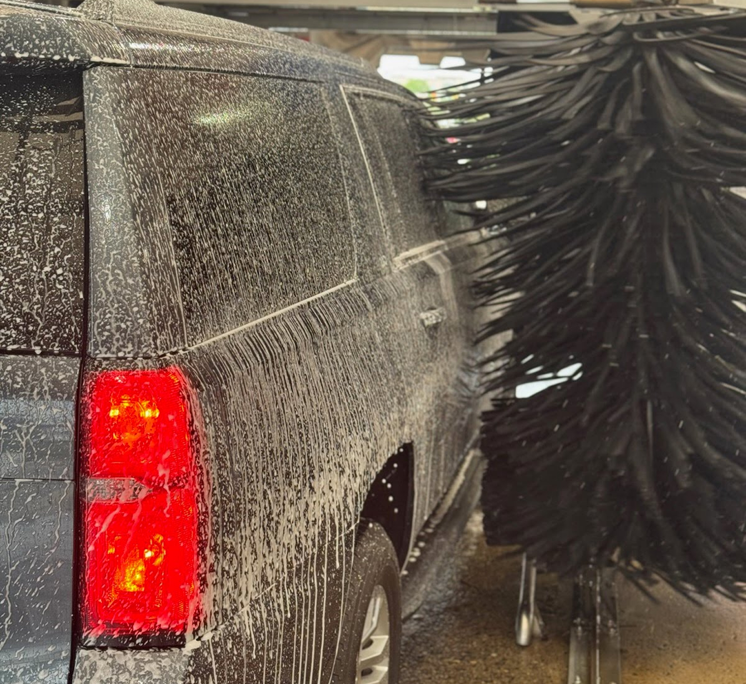 A close up photo of a grey SUV running through car wash brushes at Clean Car Wash and Detail in Fredericksburg, VA.